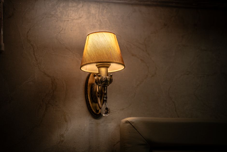 Brass wall sconce casting warm light on a dark wood wall